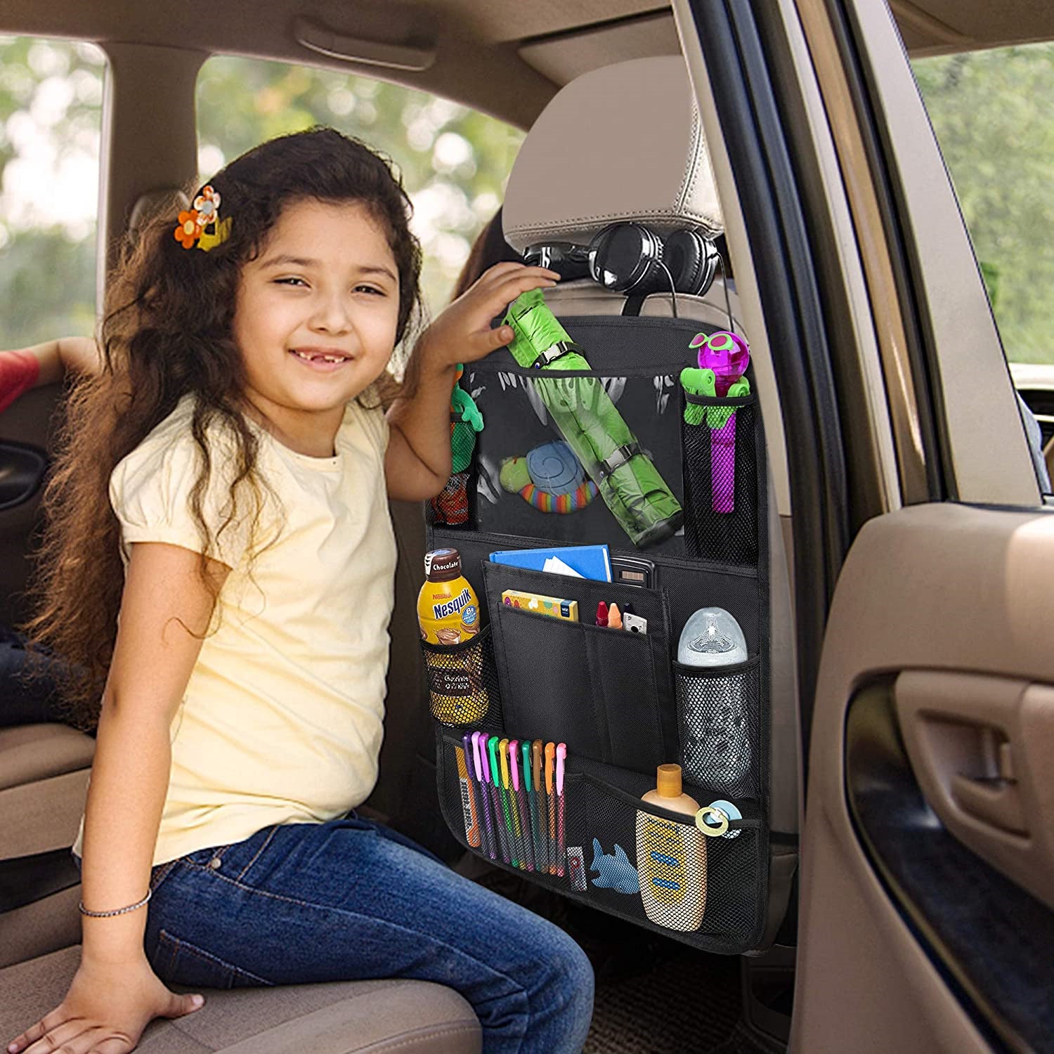 Child sitting in a car with a backseat organizer holding various items