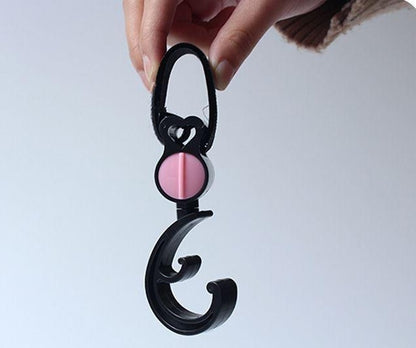 Black carabiner with a pink cap held by a hand against a light gray background