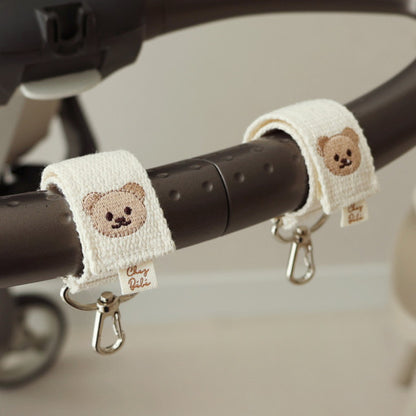 Baby stroller straps with teddy bear designs on a stroller handle.