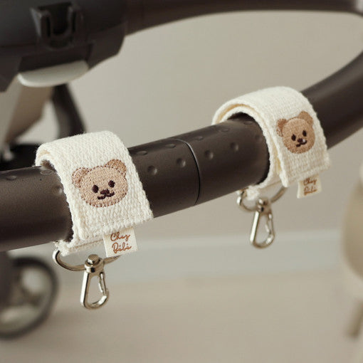 Baby stroller straps with teddy bear designs on a stroller handle.
