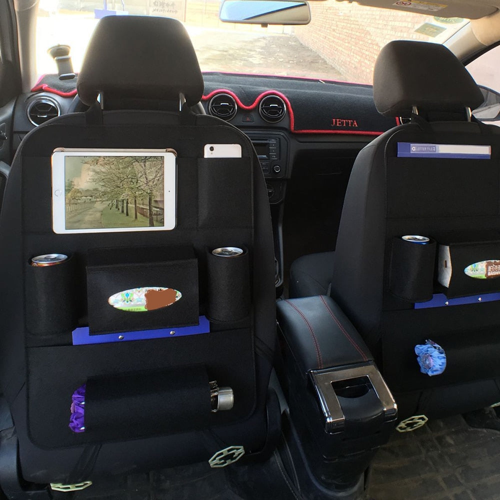 Car interior with black seat covers and various items on the backrests.