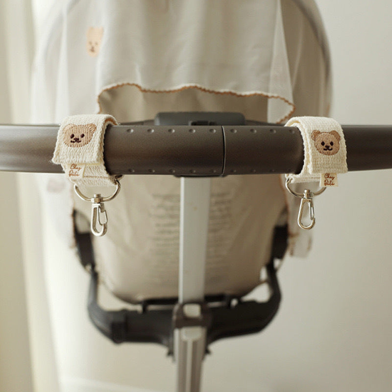 Stroller handle with teddy bear straps on a neutral background